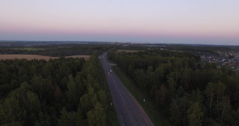 4K aerial drone video of summer sunset above highway and lush forest on the outskirts of small picturesque town Tutaev, Yaroslavl Region, Russia