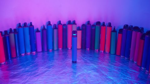 Lots of e-cigarettes and vapes in neon lighting. Concept of bad habits.