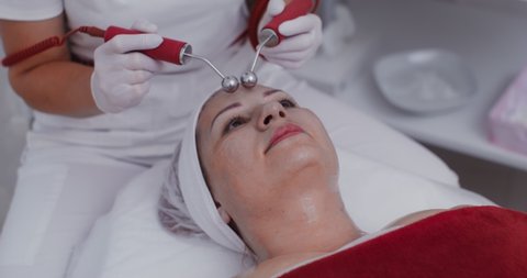 The procedure for smoothing mimic wrinkles using a laser. Facial skin massage using modern equipment in a cosmetology clinic. Video in 4k, red komodo