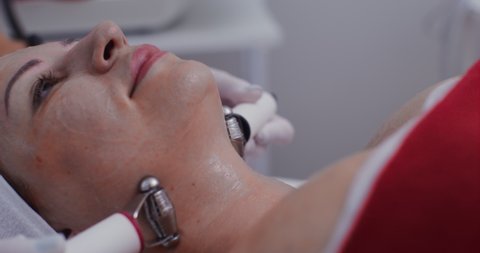 A female patient makes a lymphatic drainage tightening neck massage in a modern cosmetology clinic. Ionization and oxygenation of the skin of the decollete zone. Video in 4k, red komodo