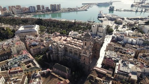 Stunning aerial pan of iconic Malaga Cathedral with port in background; Spain