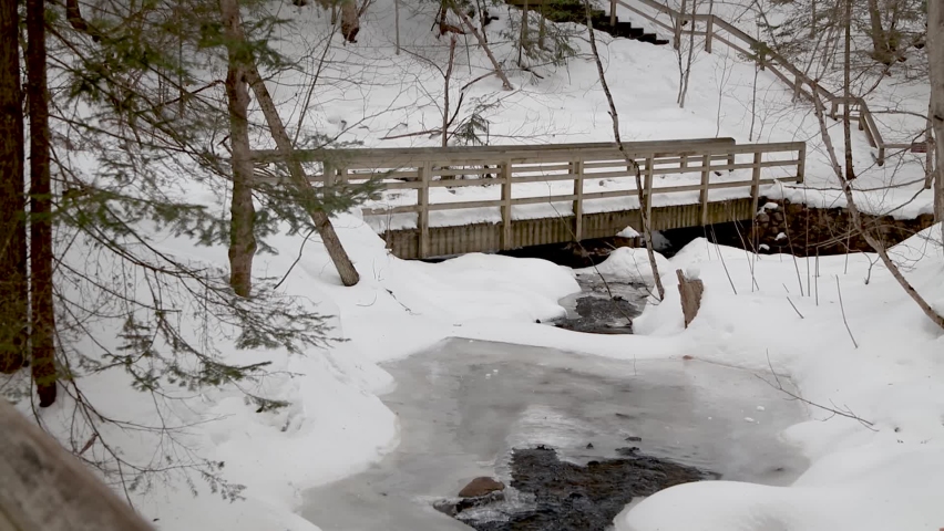 Wooden bridge across Wagner creek covered with snow in Michigan upper peninsula near Munising