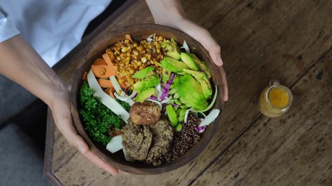Top view of female hands table setting, holding tasty healthy vegan bowl with tofu, quinoa and avocado 스톡 비디오