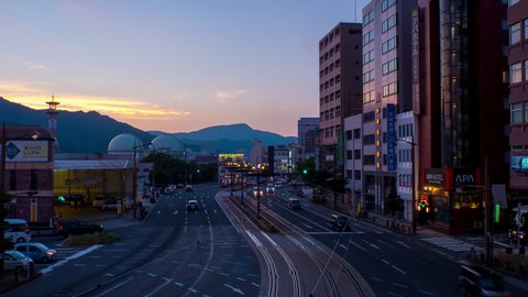 NAGASAKI, JAPAN - 28 JULY 2018: Aerial view of lively center in Nagasaki, Japan in the evening car and people traffic. Time-lapse during the sunset, zoom in