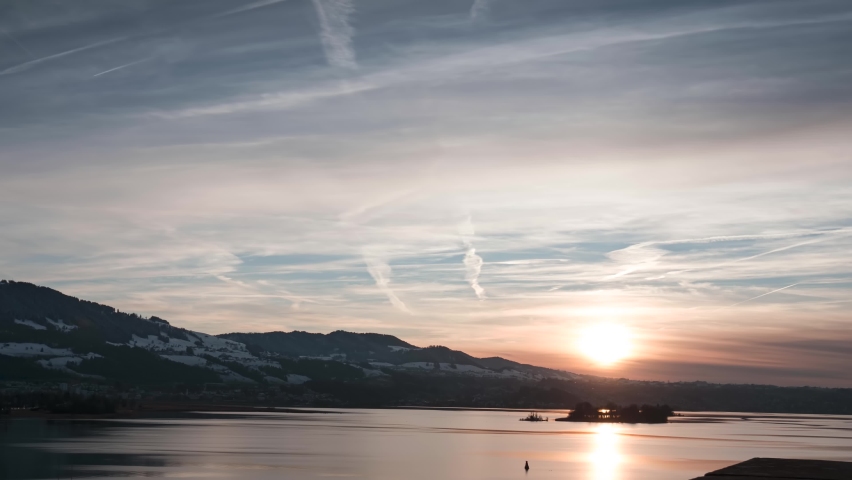 Beautiful orange sunset in the winter time with hills and lake in Switzerland