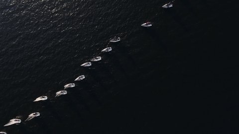 Sailing yachts lined up in the sea during a sailing regatta and cast shadows