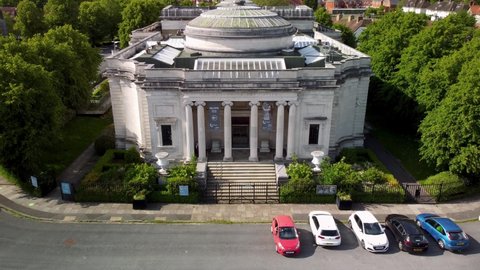 PORT SUNLIGHT, MERSEYSIDE, UK - JUNE 06, 2020: Drone shot pulling up and away from main entrance to The Lady Lever Art Gallery revealing Liverpool in the background
