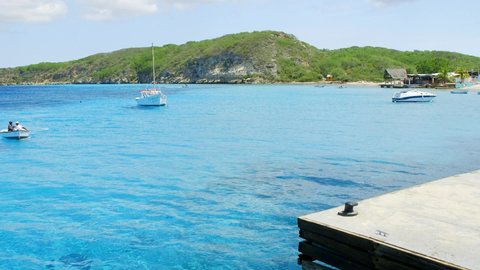 Boka Sami , Curaçao - 12 26 2021: Small dinghy docking at a jetty in the beautiful blue bay of Boka Sami on the Caribbean island of Curacao.
