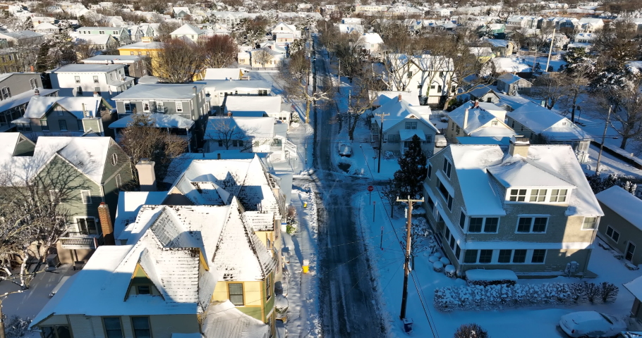 Small town in America after winter snowstorm. White snow on bright sunny day in USA. Aerial above street. Fresh snowfall.