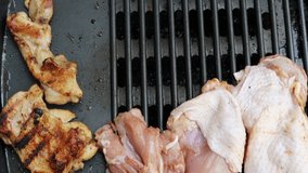 A male hand in close-up arranges raw chicken meat on an electric grill. The recipe for chicken meat and wings. Cooking with an electric grill without oil.  Outdoor cooking. Shot from above.