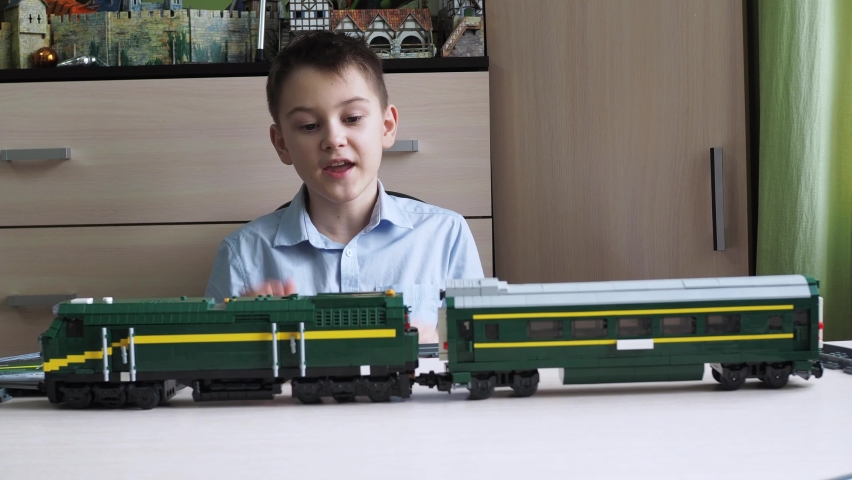 a boy sitting at a table shows a locomotive with cars. tell me about the constructor. review of a young blogger about toys