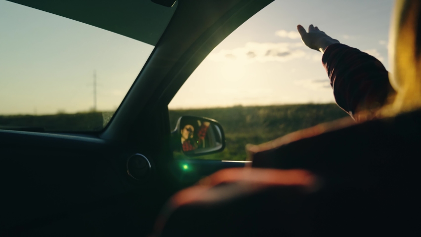 Hand happy girl from car window sunset. happy man travels. hand sunset. free girl travels. smile young girl trip driving car. wind develops hair rays sunset. sun glare from car window on child hand.
 | Shutterstock HD Video #1087264529