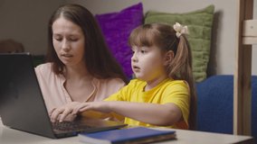 mom explains kid school topic lesson. happy family. helping my daughter with homeschooling. little student studies laptop with her mother. teacher helps kid understand topic lesson computer. teamwork.