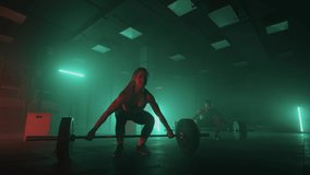 A man and a woman in a colored neon red and blue light in slow motion lift heavy barbells over their heads. Strength and power training with heavy weight. The concept of athletic and strong couples - Powered by Shutterstock - Get 15% off with code: PIKWIZARD15