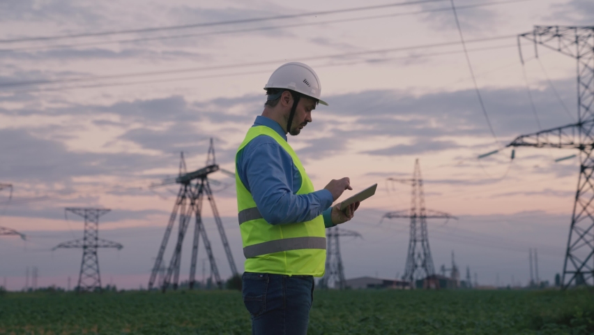 Silhouette of an electrical engineer in hard hat at sunset with tablet. business technology industry. concept electrical voltage tower towers. high voltage substation with distribution cables. energy Royalty-Free Stock Footage #1087272398