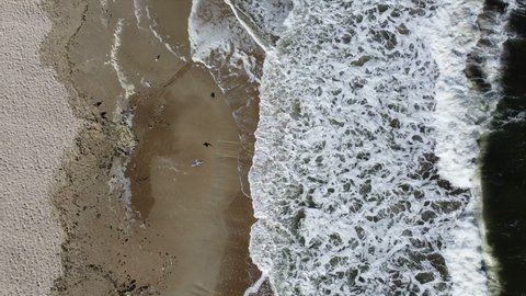 Sea waves with white foam on top. Beautiful seascape landscape waves on sea sandy coast on sunny day. Texture of foam on waves, stormy sea, sand beach sea scenery. Aerial drone view natural background