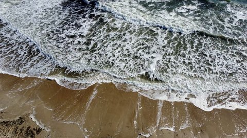 Sea waves with white foam on top. Beautiful seascape landscape waves on sea sandy coast on sunny day. Texture of foam on waves, stormy sea, sand beach sea scenery. Aerial drone view natural background