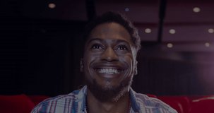Animation of letters over smiling african american man eating popcorn in cinema. popcorn day and celebration concept digitally generated video.