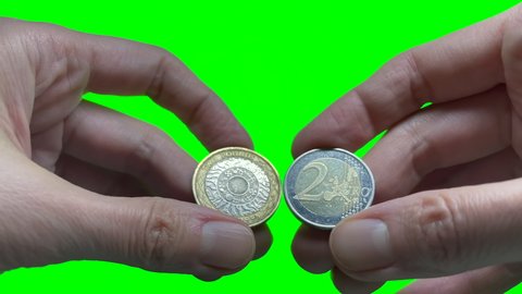 Hands hold a Pound and Euro coin on green screen background. United Kingdom and the European Union relationships after Brexit. Money rate. Currency, money exchange concept. 4k video