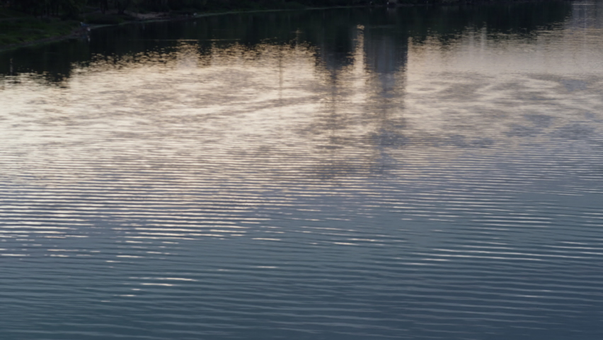 Calm river ripples reflecting abstract cityscape drone shot. Blue water texture. Relaxing seascape waves glowing flowing at slow pace. Beautiful urban buildings light reflection in waterway concept. - Powered by Shutterstock - Get 15% off with code: PIKWIZARD15