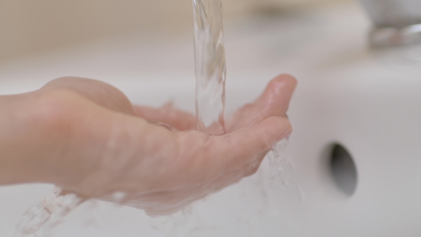 Slow Motion. Closeup of Human Hand Under Stream of Pure Water From Tap. Child Palm Under Stream of Water Slow Motion. Little Girl in Bathroom at Home Checking Temperature Touching Running Water.  Royalty-Free Stock Footage #1087283372