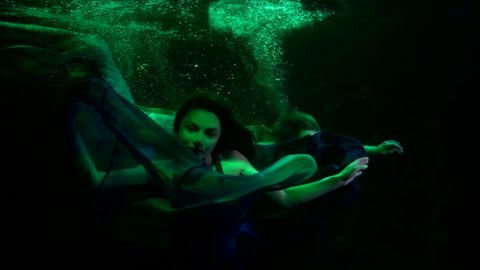 underwater mystery and magic, woman and mermaid are floating in deepness and darkness