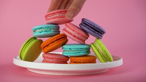 Woman's hands take delicious colorful french macaroons from the plate. 8 March.