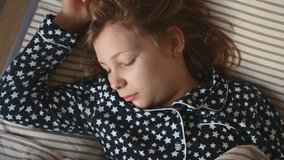 4K 60fps video of  teen child girl in pajamas lazy wake up in the morning stretching in bed at holidays