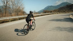 Woman cycling. Cyclist riding bicycle in helmet and cycling apparel. Cycling in mountains. Triathlete training for race competition. Female athlete pedaling on bike during training workout