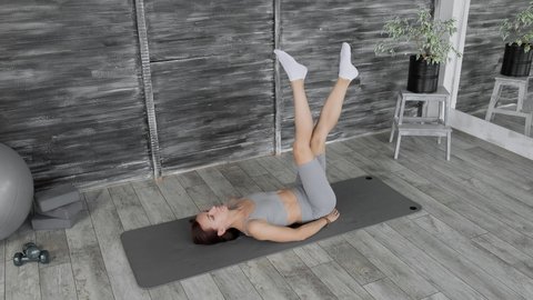 Fitness woman working out for better health indoors. Brunette woman making abs exercises. Young sporty woman training abdominal muscles on mat. Bodycare and fitness concept. 4K, UHD