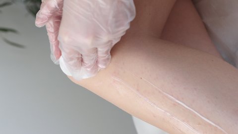 Depilation procedure with wax on the legs. Waxing depilation in beauty salon. Beauty concept. Vertical video
