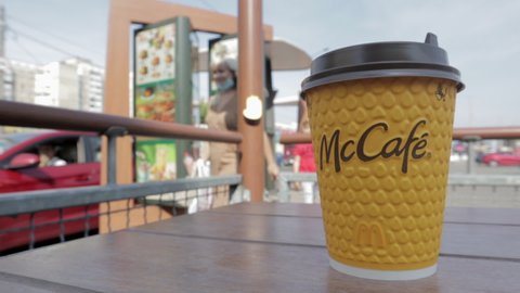 Yellow cardboard coffee cup from McDonald's. Mc Cafe paper glass drink. One coffee cup on the table with hot tea or coffee. Menu in a fast food restaurant. Ukraine, Kiev - September 12, 2021.