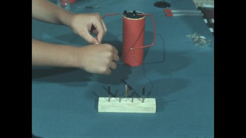 1960s: Finger spins coiled nail on turnstile. Child connects coiled nails to battery wires. Coiled nail spins on turnstile.