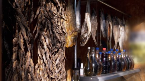 Dried Small Fish Hanging on Hooks Hang on the Open Stalls of the Street Market. Salted sea fish for sale in rays of sunlight. Sea catch. Trade seafood on open counters, showcases, outside. Summertime.