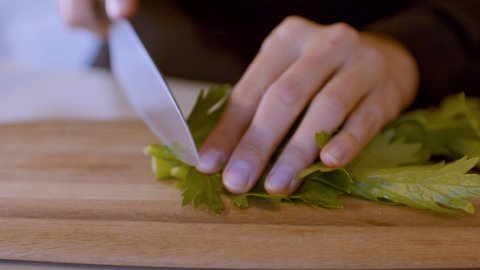 Slicing of fresh celery on wooden board