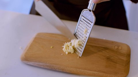 Fresh Garlic Clove crushed in the grater on the Wooden Cutting Board Macro
