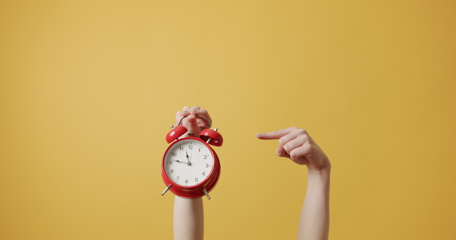 Woman gesturing with her hands with Red alarm clock on isolated on yellow background. hurry up, relive it Woman Hands gestures, and shows that he must hurry. Retro Red Clock. Alarm Time.