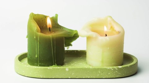 Igniting candles on white background. Wooden stick lights candles on high framerate. Natural wax candles on ceramic plate