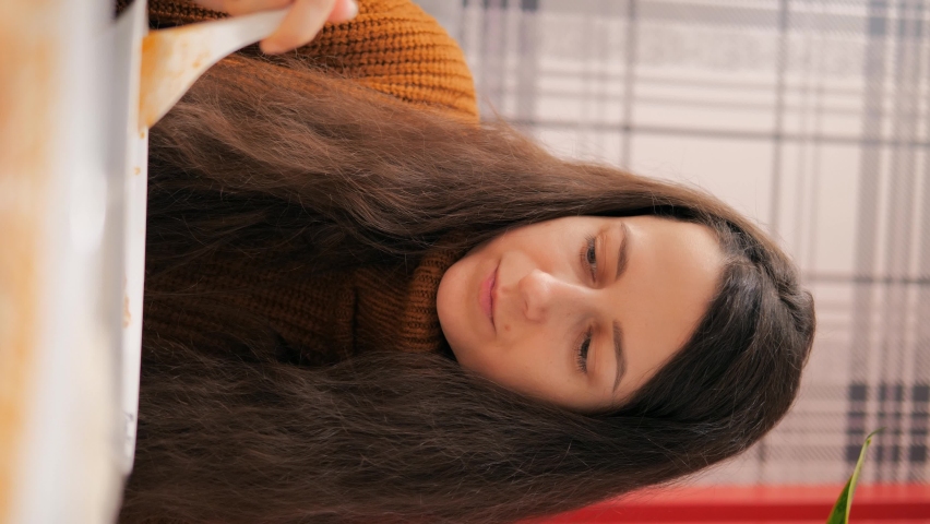 Portrait of a young beautiful woman in a cafe eating spicy soup from Asian cuisine. Vertical video