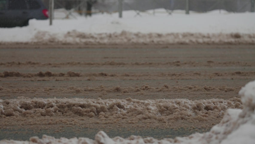 City roads during heavy snowfalls. Cars drive through winter mud and snow