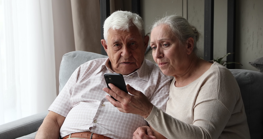 80s older spouses sit on sofa look at cellphone screen read sms scream with joy celebrate great fantastic news got, hugging feel overjoyed. Jackpot, lottery victory, pension payments increase concept Royalty-Free Stock Footage #1087319495