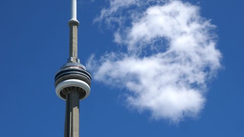 TORONTO, ONTARIO, CANADA on June 12th, 2020: CN Tower with blue sky and white cloud passing. The CN Tower is a 553.3 m-high communications and observation tower located in the downtown core.