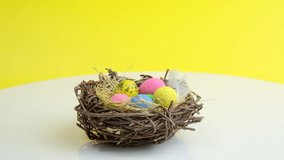 Rotating easter eggs in nest. Holiday celebration concept. Minimal holiday season concept, yellow background, copy space