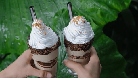 Close up of two yummy cacao milkshakes with chocolate syrup, sweet whipped cream and cookies decoration