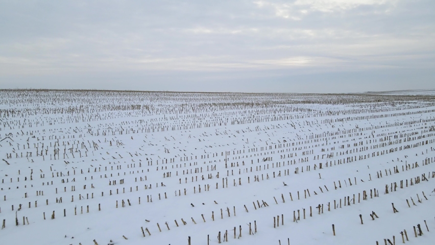 Flying through winter farm fields with hills in the background