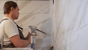 Worker applies the fugue to the trowel. Applying grout to the joints between tiles, grouting tiles.