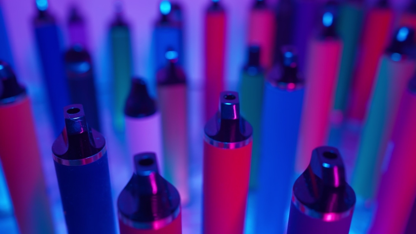 Lots of e-cigarettes and vapes in neon lighting. Concept of bad habits. | Shutterstock HD Video #1087331927