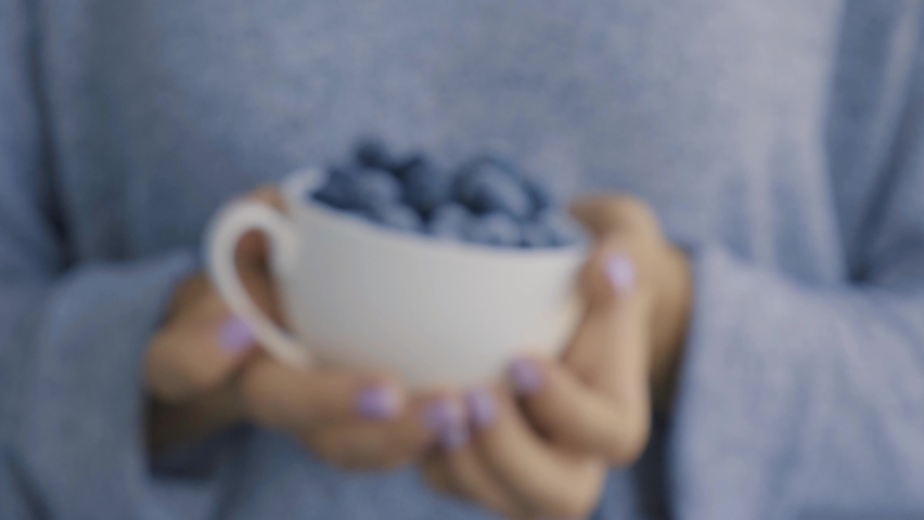 Woman holding bowl with Frozen blueberry fruits. Harvesting concept. Female hands collecting berries. Healthy eating concept. Stocking up berries for winter Vegetarian vegan food | Shutterstock HD Video #1087332323