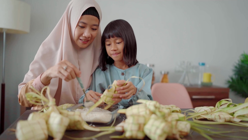 muslim mother and daughter make ketupat for eid mubarak celebration with family Royalty-Free Stock Footage #1087332695