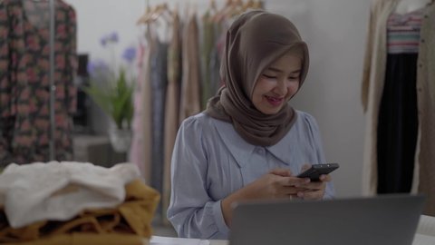 muslim businesswomen using mobile phone working in her workshop